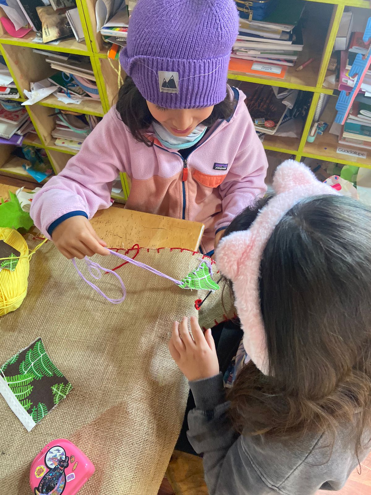 Dos estudiantes bordando juntas en un proyecto de aula